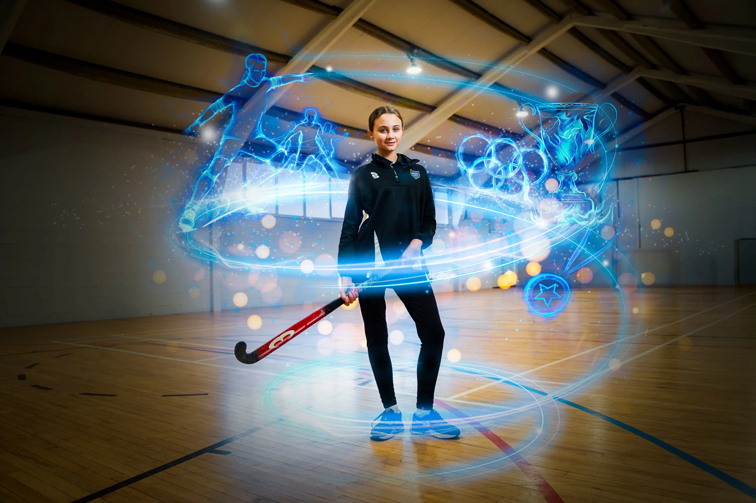 Female pupil in sports kit holding a hockey stick inside a indoor sports hall, surrounded by glowing digital sports graphics