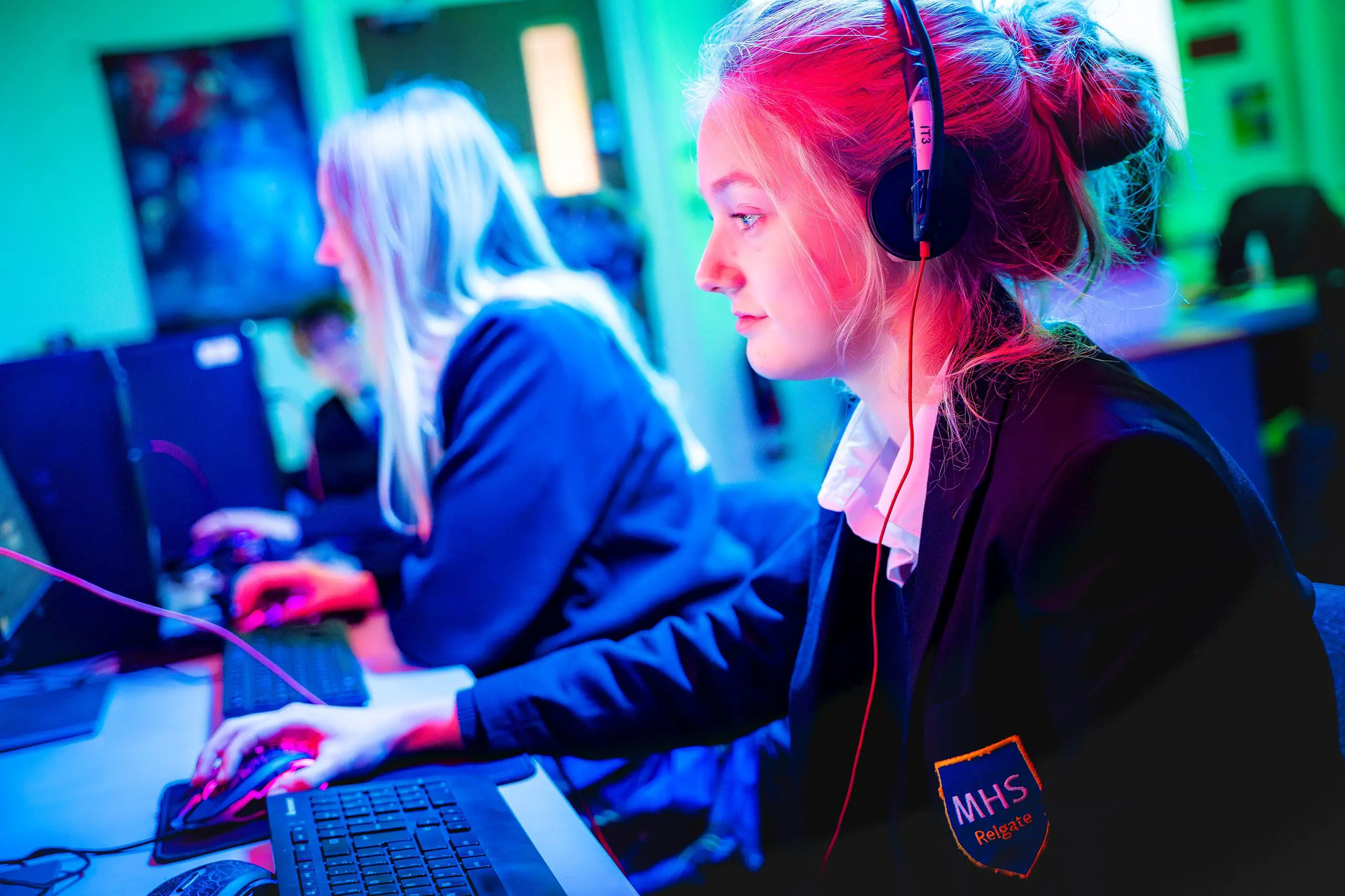 Female student wearing headphones while working on a computer in a modern classroom setup