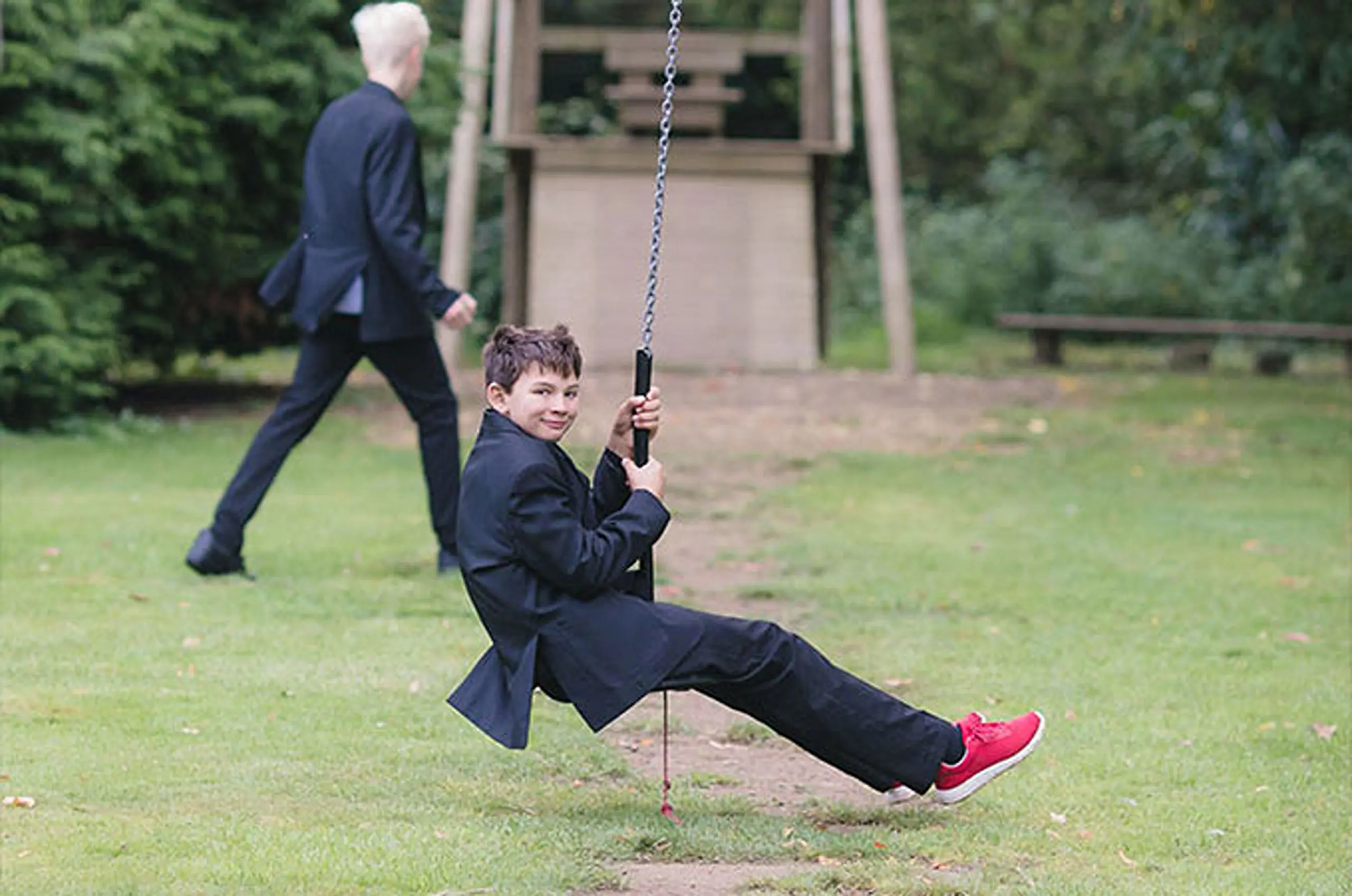 Pupil enjoying a zip line in the school playground with another student in uniform walking in the background